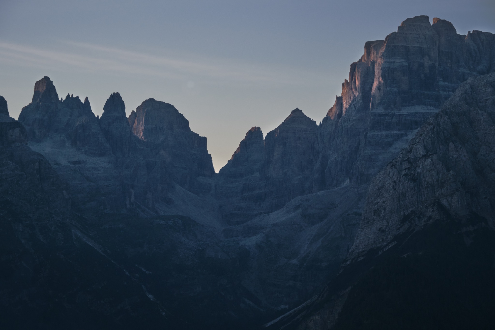 Pareti delle Dolomiti di Brenta in ombra, con luce rosata sulle cime e un varco di cielo al centro